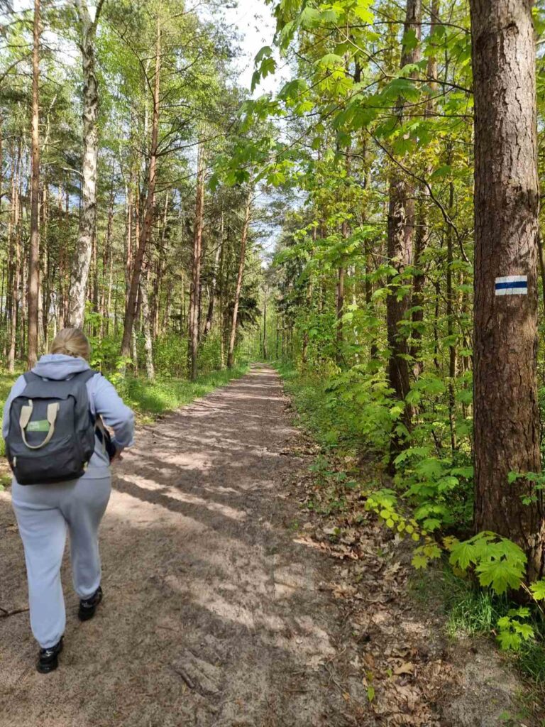 Aleksandra walking in the forest with green leaves